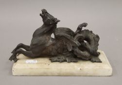 A bronze figure of a mythical hippocampus, on a white marble base. 22.5 cm long overall.