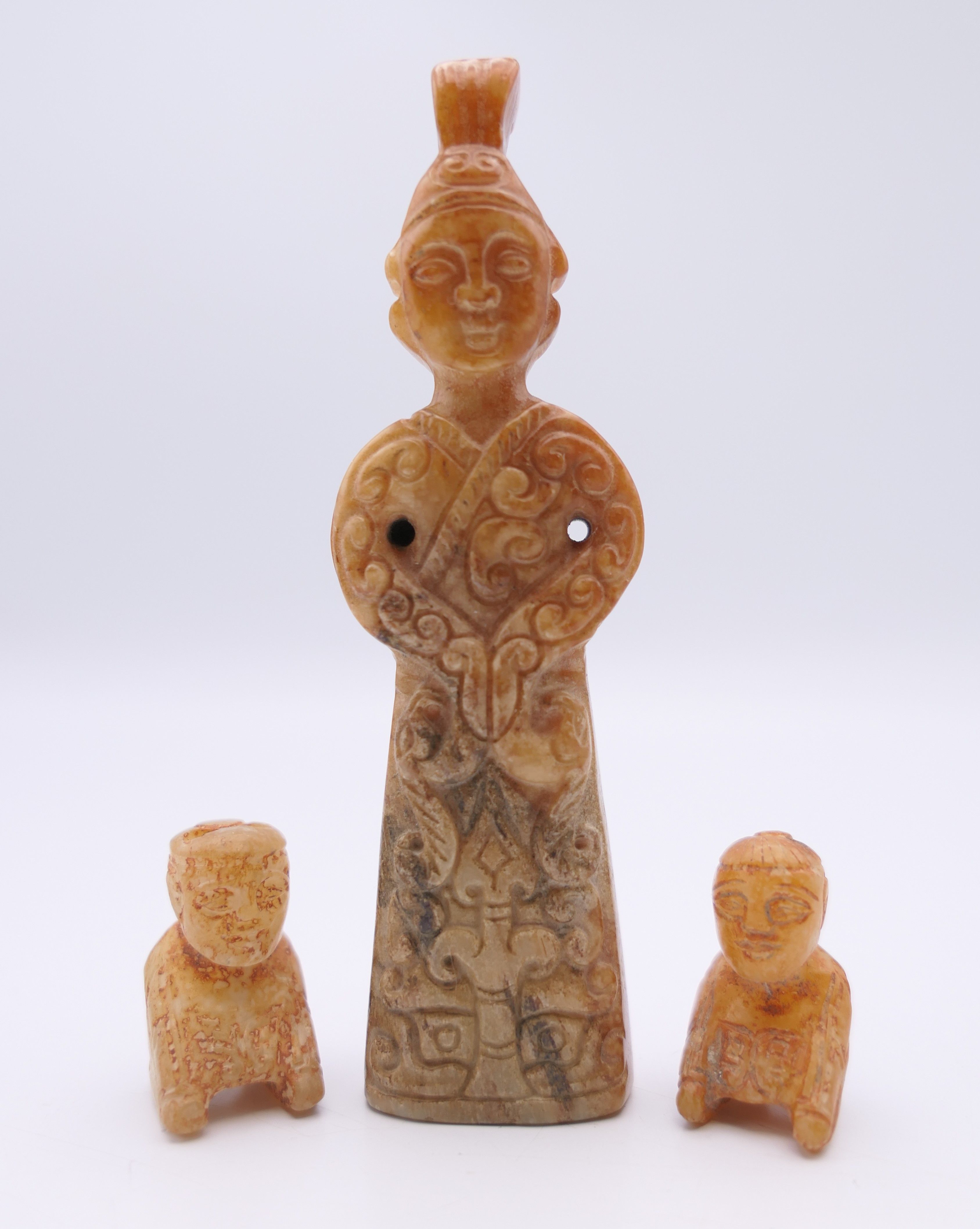 A Chinese jade standing male figure, together with two smaller kneeling male figures, Han Dynasty.