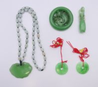A Chinese green jade pendant necklace and four pendants. The largest pendant 5 cm diameter.