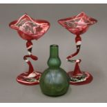 A Loetz type glass vase and two red ground glass vases (one damaged). The former 11 cm high.