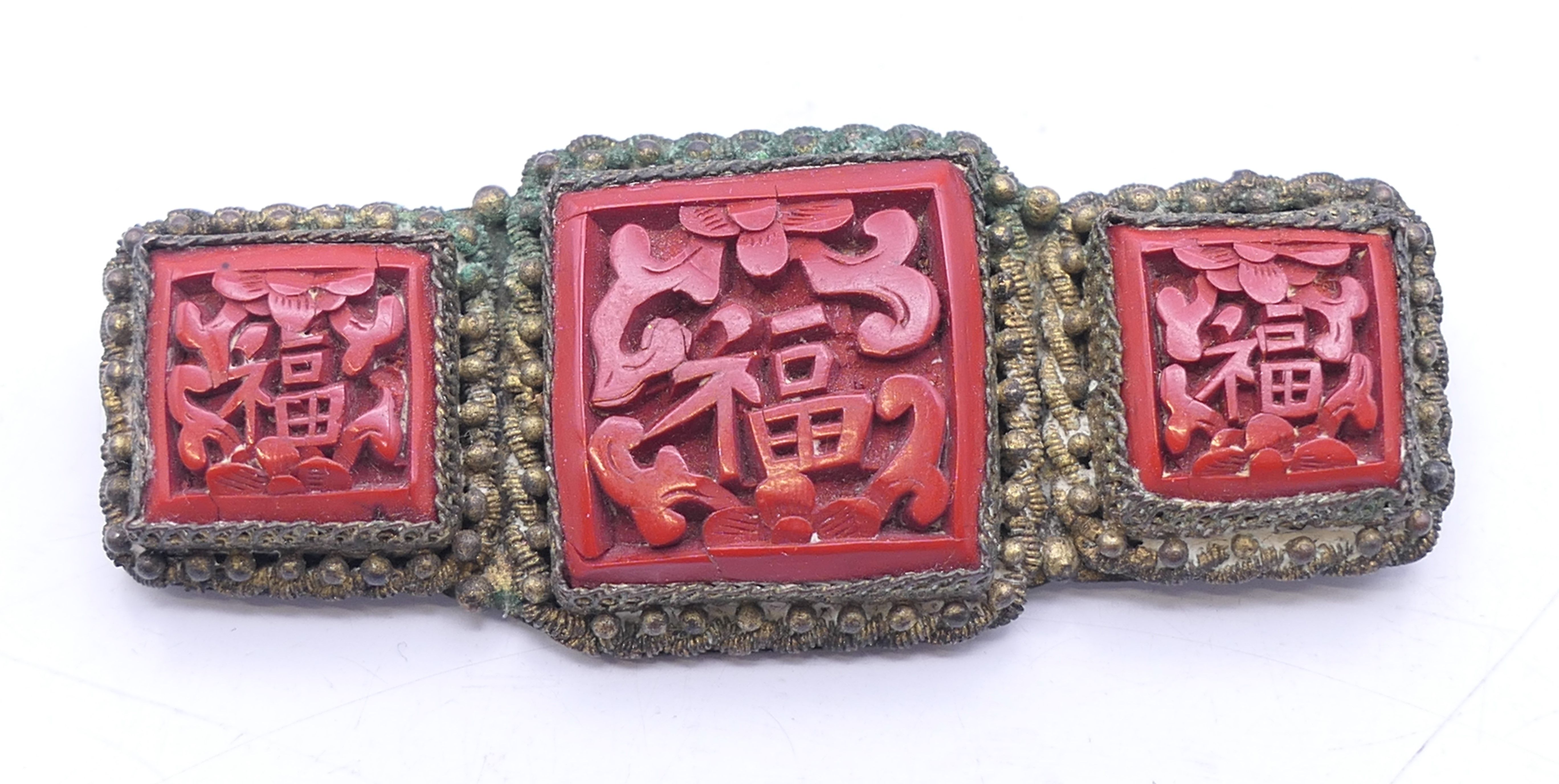 A Chinese cinnabar mounted brooch. 5.5 cm wide.