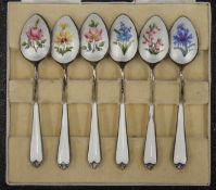 A cased set of six enamel decorated silver teaspoons. The case 13 cm wide.