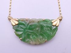 An 18 ct gold and jade pendant necklace. The pendant 3.5 cm wide. 5.9 grammes total weight.