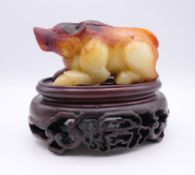 A Chinese brown, red and black jade pig, together with a modern oval wooden stand. 8.5 cm long.