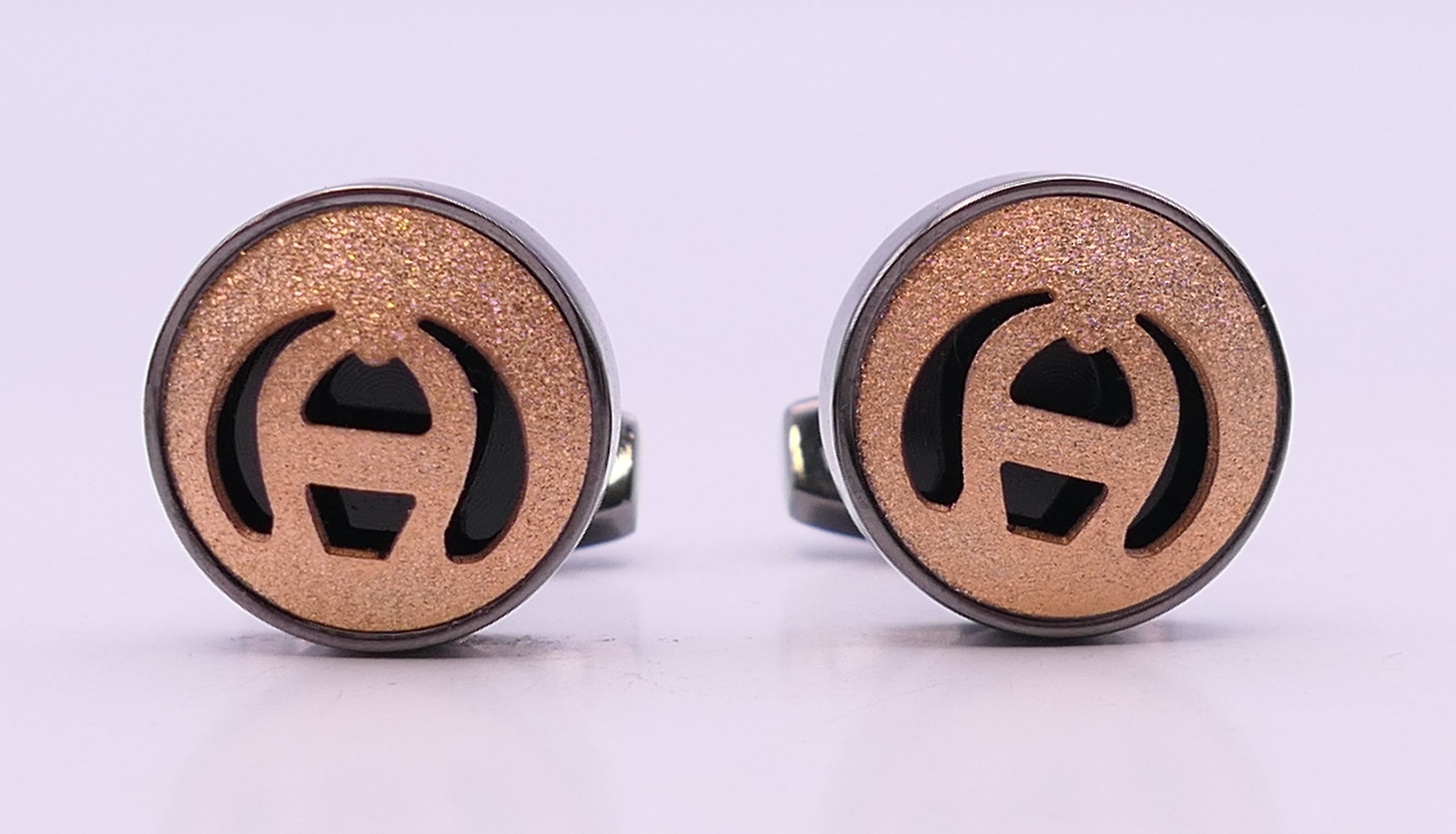 A pair of Aigner cufflinks, in a Penrose of London box. 1.75 cm diameter.