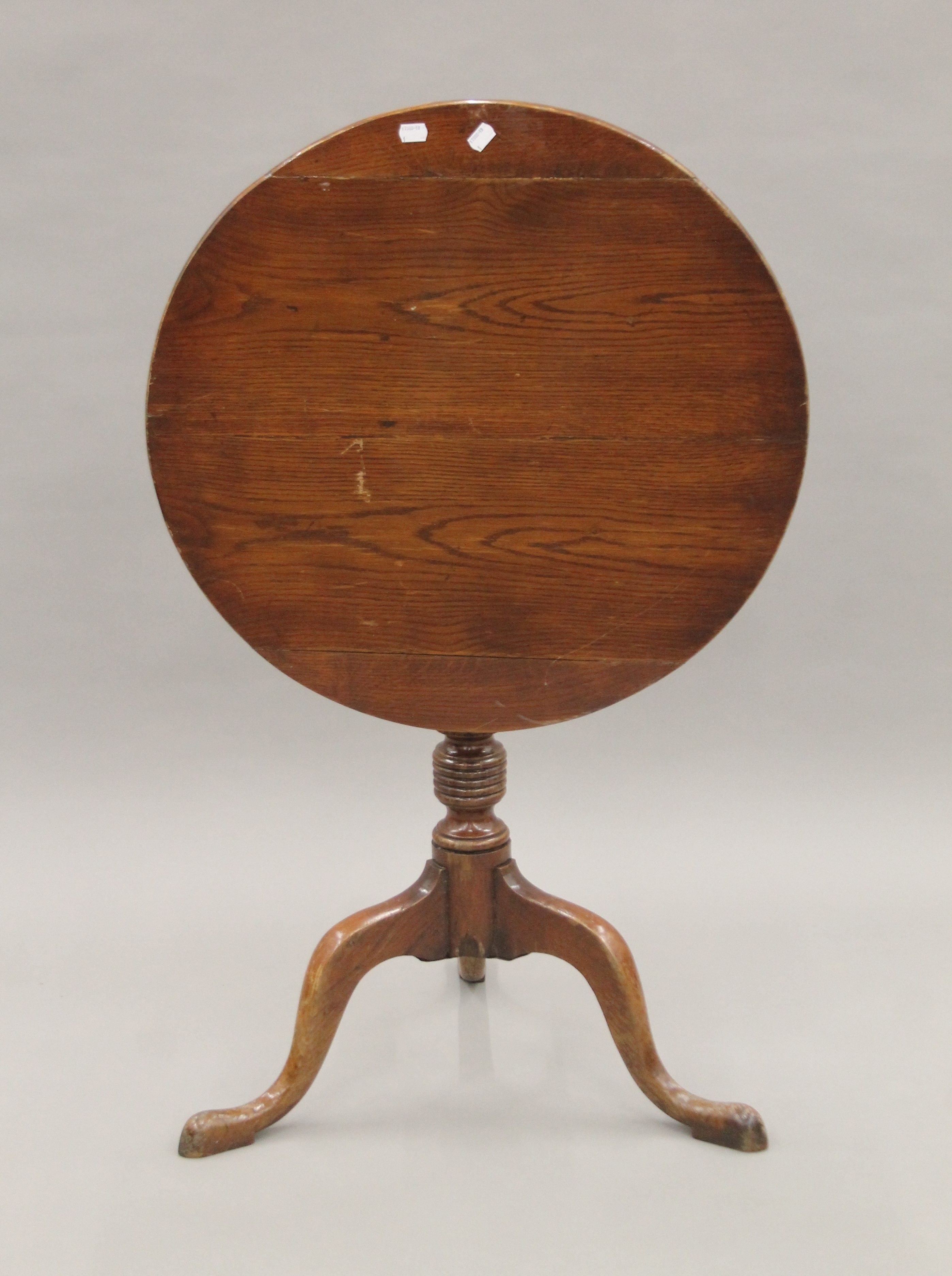 A 19th century oak and elm tilt top tripod table. 63 cm diameter.