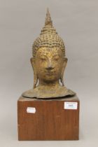 A large antique gilded bronze Buddha head on a wooden stand. 42 cm high overall.