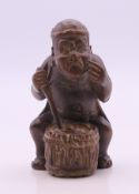 A netsuke formed as a man playing a drum. 5.5 cm high.