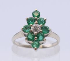 A white gold, emerald and diamond nine stone cluster ring. Ring size L. 2.7 grammes total weight.
