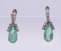 A pair of white gold emerald and diamond earrings.