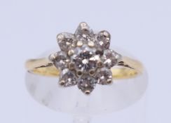 An 18 ct gold daisy cluster ring. Ring size J/K. 2.6 grammes total weight.