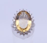 An 18 ct white gold citrine and diamond oval cluster ring. Ring size N. 8.3 grammes total weight.