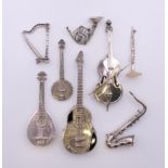 A collection of miniature silver instruments, including: harp, cello, flute, guitar, banjo,