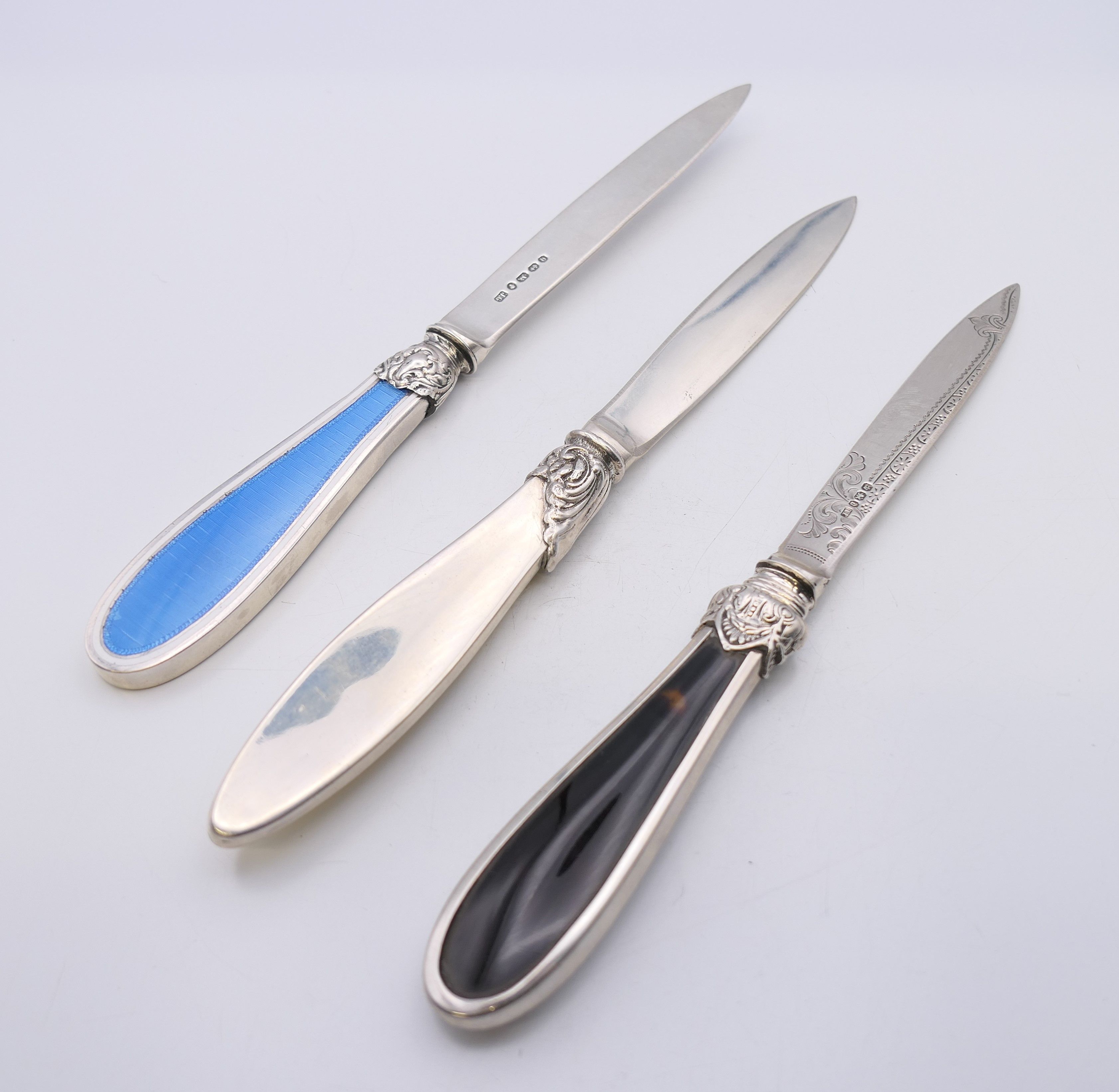 Three silver letter openers, two with enamel decoration and one with tortoiseshell.