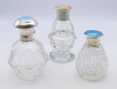 Three silver and enamel lidded glass dressing table bottles. The largest 11 cm high.