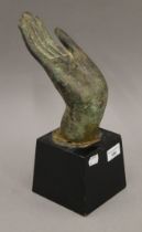 A large antique bronze hand of Buddha, on a fixed wooden stand. 31 cm high.