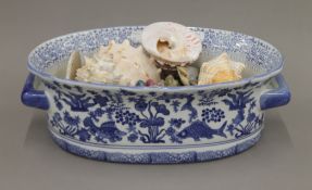 A collection of sea shells and minerals in a blue and white jardiniere. The jardiniere 40 cm long.