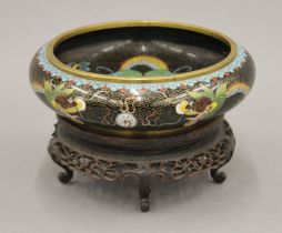 A Chinese cloisonne bowl decorated with a dragon, on a wooden stand. The bowl 20 cm diameter.