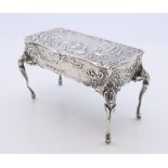 An embossed silver trinket box formed as a table, import marks for London 1899.