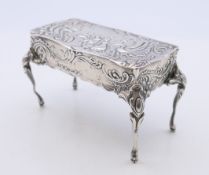 An embossed silver trinket box formed as a table, import marks for London 1899.