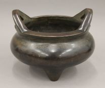 A Chinese twin handled bronze censer of circular form on three feet, seal mark to base.