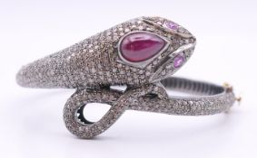 An unmarked white metal diamond set bangle in the form of a snake. 6 cm internal diameter.