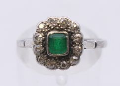 A platinum, diamond and emerald ring. Ring size N. 3.8 grammes total weight.