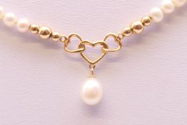 A small single strand pearl necklace with 14 ct gold heart shaped link. 44 cm long.