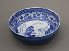 A Japanese blue and white porcelain bowl decorated with figures in mountainous landscape.