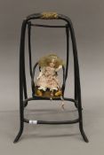A Victorian miniature porcelain doll, on a swing. 32.5 cm high overall.