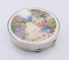 An early 20th century silver and enamel compact, the lid decorated with a floral garden scene.