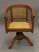 An early 20th century caned revolving desk chair. 60 cm wide.