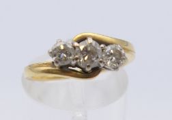 An 18 ct gold three stone diamond ring. Ring size L/M. 3.7 grammes total weight.