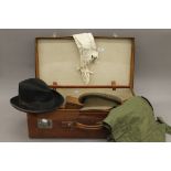A vintage leather suitcase containing gentleman's clothes, etc., including a military hat.