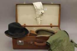 A vintage leather suitcase containing gentleman's clothes, etc., including a military hat.