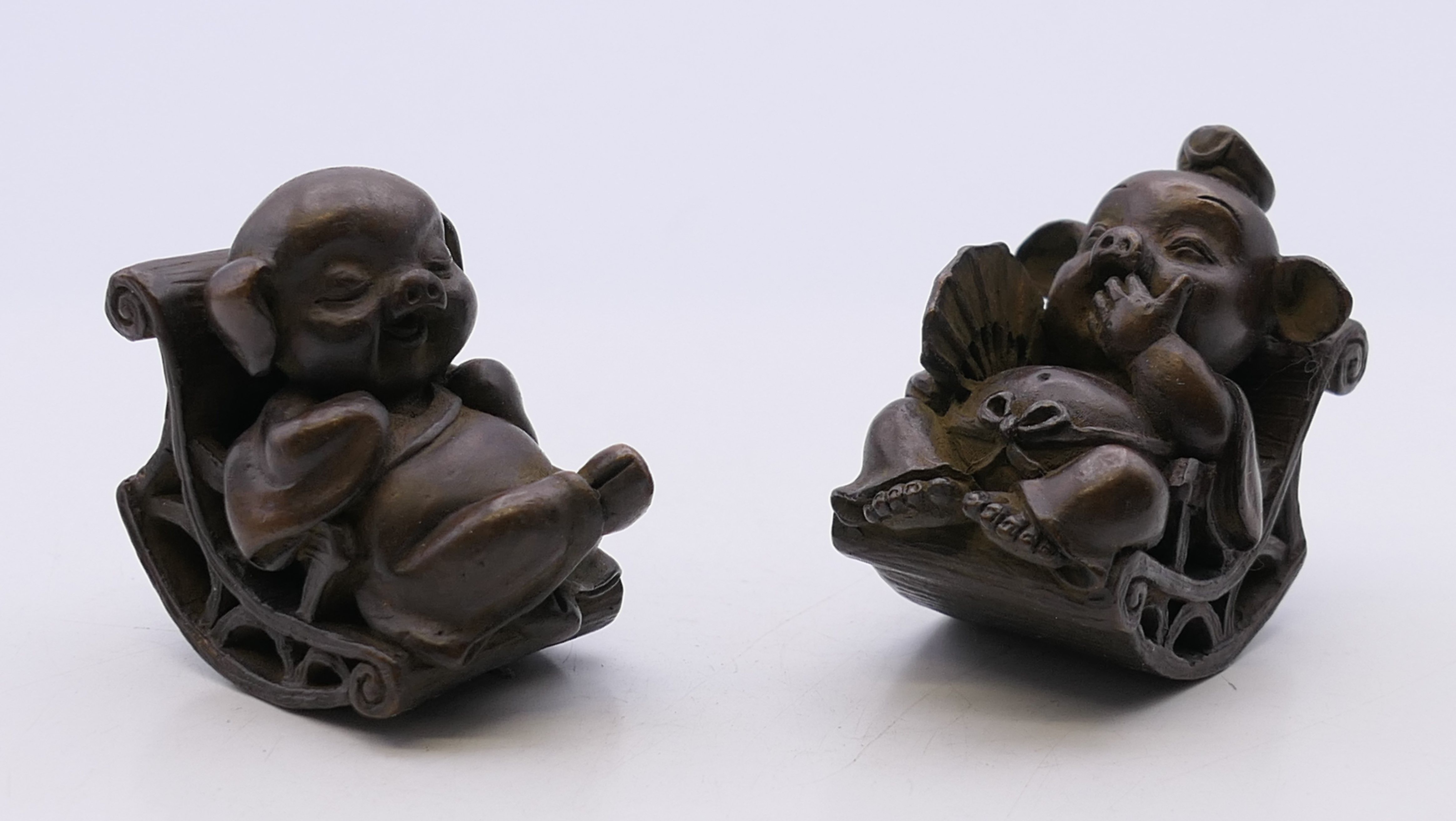 A pair of bronze models of pigs on rocking chairs. Each 4 cm high.