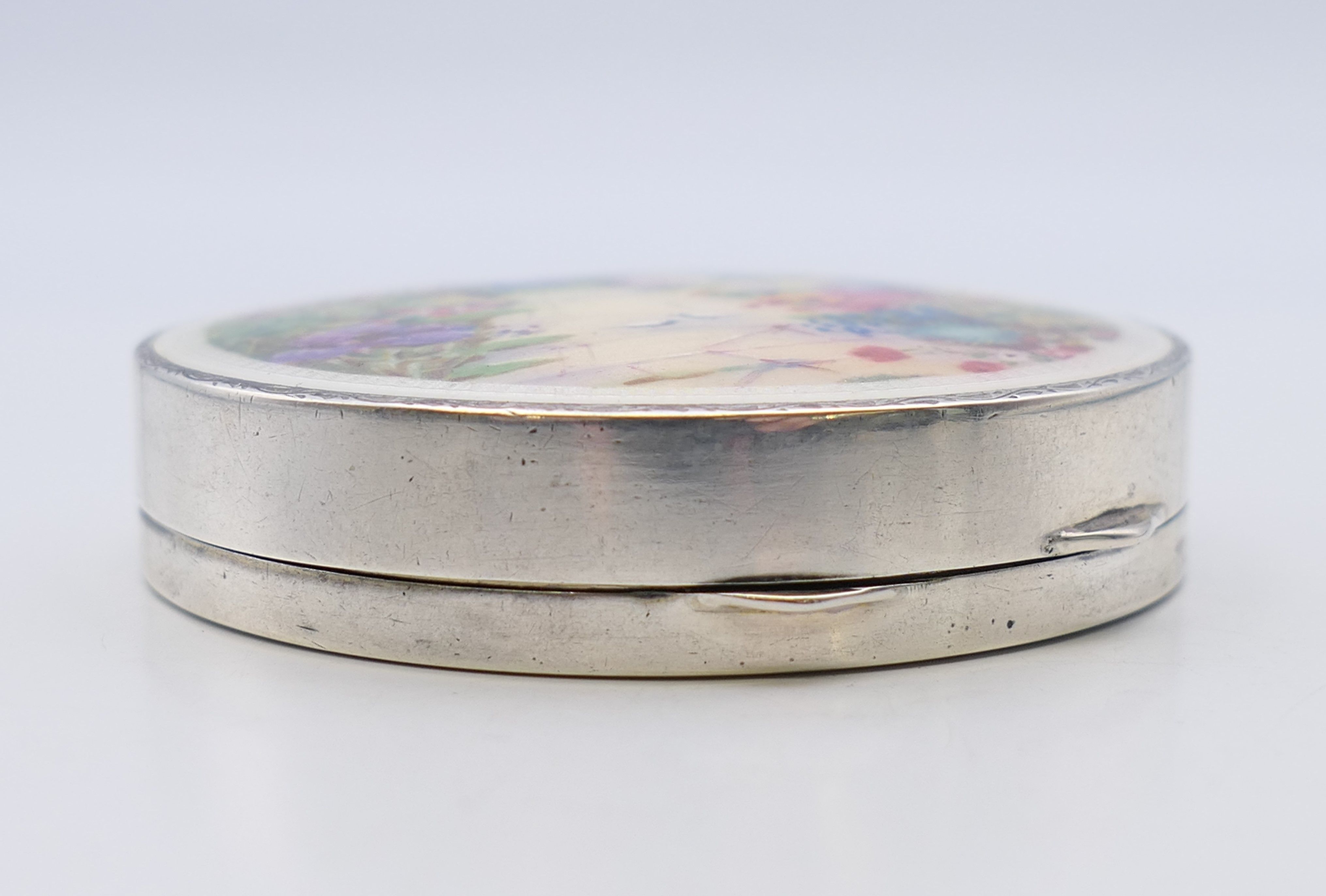 An early 20th century silver and enamel compact, the lid decorated with a floral garden scene. - Image 3 of 6