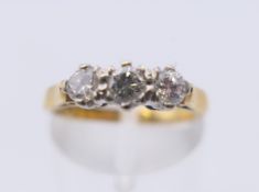 An 18 ct gold three stone diamond ring. Ring size J/K. 3.5 grammes total weight.