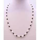 A pearl and black bead necklace with 9 ct gold clasp. 44 cm long.