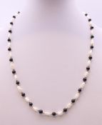 A pearl and black bead necklace with 9 ct gold clasp. 44 cm long.