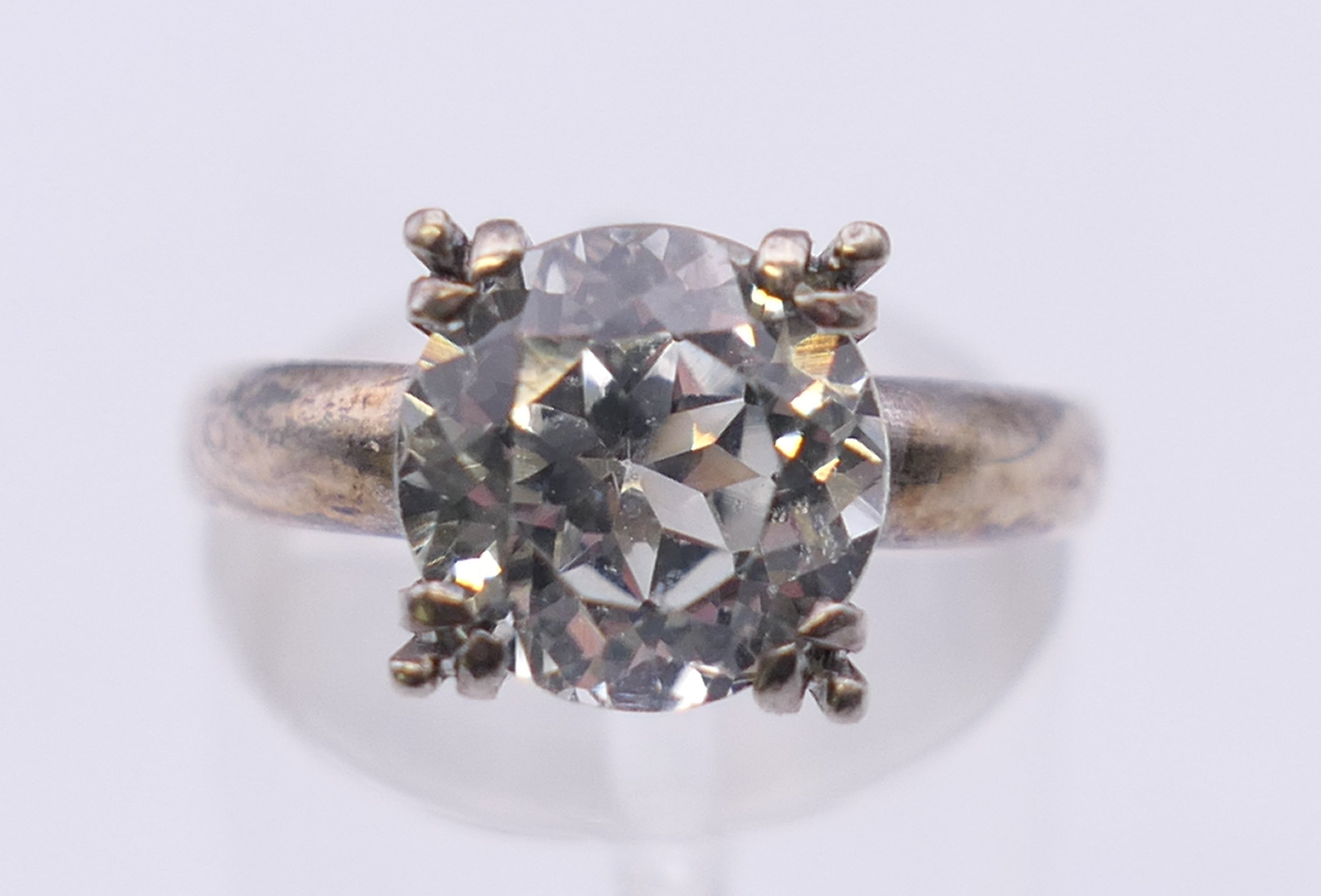 An unmarked solitaire ring, possibly white sapphire. Ring size M/N.