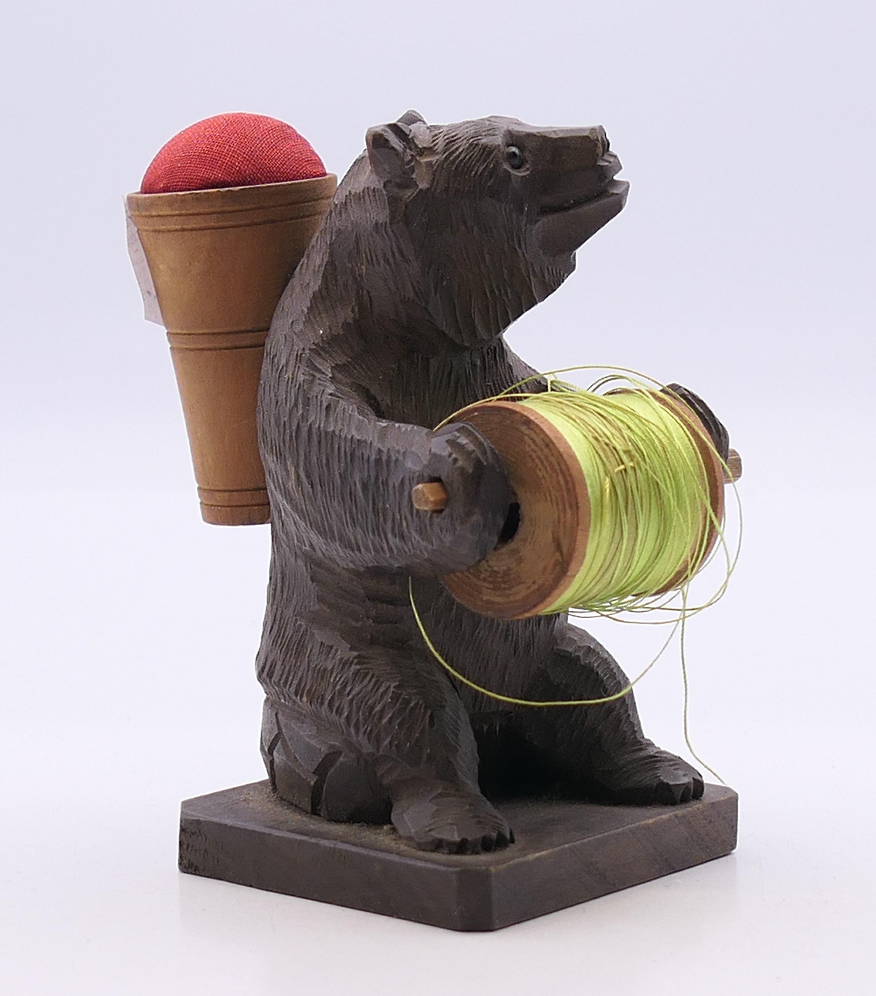 A Blackforest cotton reel holder and pin cushion formed as a bear. 9 cm high.