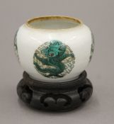 A Chinese bowl with green design motif and four character mark to base, on a carved wooden stand. 7.