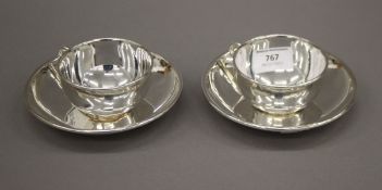 A pair of silver plated cups and saucers. The cups 8 cm diameter.