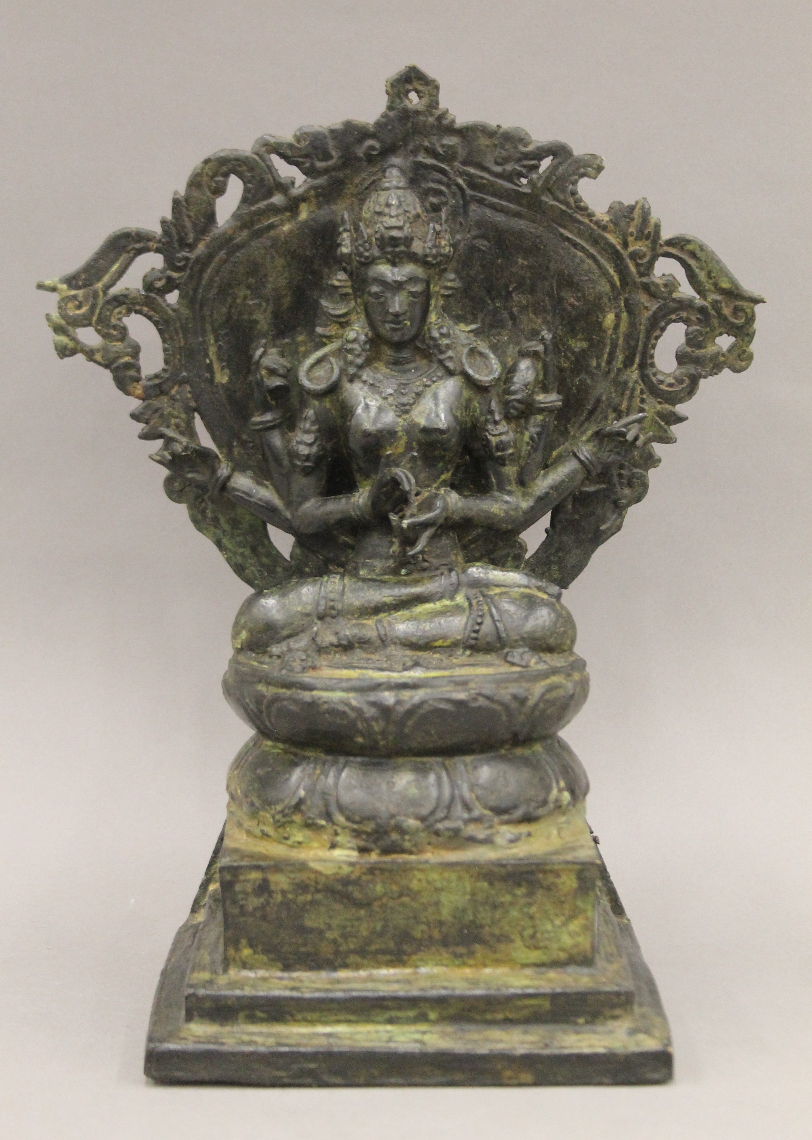 A Tibetan bronze figure of a six armed deity seated on a lotus leaf, on a stepped base. 34 cm high.