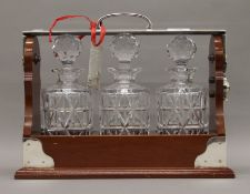 A three bottle silver plate mounted tantalus. 34 cm wide.