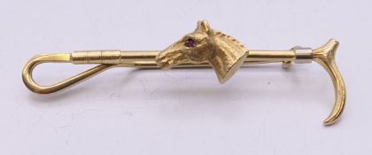 A 9 ct gold bar brooch formed as a riding crop and horse's head with gem set eye. 6 cm long. 6.