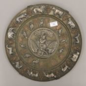 A Middle Eastern silvered copper and brass charger, set with various animals surrounding a deity.
