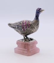 An unmarked silver and enamel gem set model of a goose mounted on a rose quartz stepped plinth base.