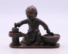 A bronze model of a boy cooking. 6.5 cm high.